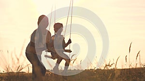 Amusement park dream concept. Happy girl swinging on a swing in the park at sunset. child plays with wooden swing