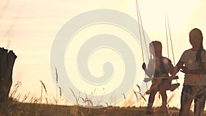 Amusement park dream concept. Happy girl swinging on a swing in the park at sunset. child plays with wooden swing