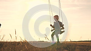 Amusement park dream concept. Happy girl swinging on a swing in the park at sunset. child plays with wooden swing