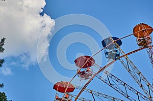 Amusement park ferris wheel, blue sky with clouds, green trees