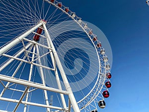 Amusement park. ferris wheel made of white metal. a huge wheel with booths for tourists in white and red. carousel ride