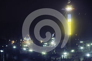 Amusement park at night - view from ferris wheel, carousels and attractions in motion