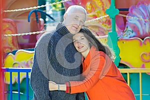 Amusement park outdoor family portrait of hugging adult daughter and senior father