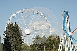 Amusement park. People having fun. Ferries wheel and roller coaster.