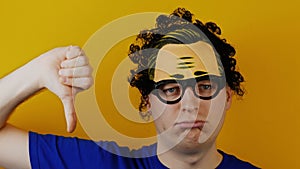 Amusing and comical curly man shows thumb down or dislike