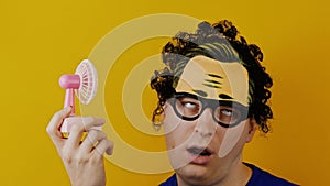 Amusing and comical curly man with toy pink fan