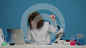 Amusing crazy chemist analyzing liquid in test tube at desk