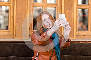 Amusing girl making funny faces and taking photos of herself