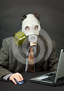 Amusing person in gas mask works with computer photo