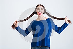 Amusing pretty woman holding her two long braids and shouting