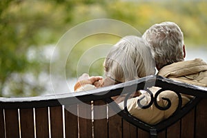 Amusing senior couple sitting on bench in park