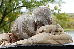 Amusing senior couple sitting on bench in park