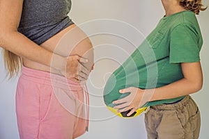 Amusing son. Pregnant beautiful woman amusing her little son while putting yellow ball under his green shirt