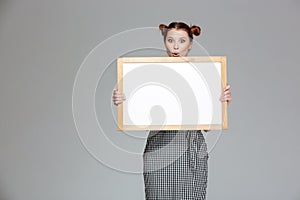 Amusing surprised young woman holding blank whiteboard