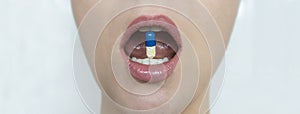 An analgesic and antipyretic pill between the beautiful teeth of a young girl. Prevention and treatment of symptoms of influenza,