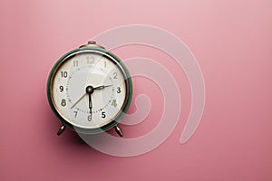 Analog alarm clock on pink table background