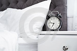 Analog alarm clock on table in bedroom