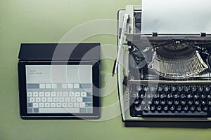 Analog and digital typewriters lie on the green surface. Continuity of generations, technology development concept