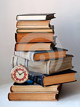 Analog retro alarm clock and a heap of old books