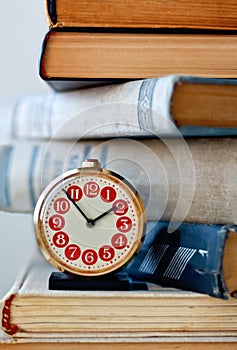 Analog retro alarm clock on a heap of old books