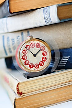 Analog retro alarm clock on a heap of old books