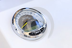 Analog tachometer on the white dashboard control panel of the motor boat