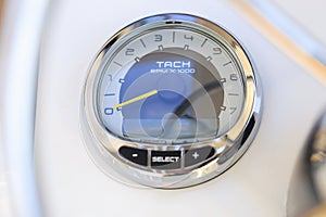 Analog tachometer on the white dashboard control panel of the motor boat