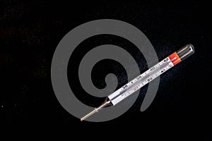 Analog thermometer on black background with blue splashes photo