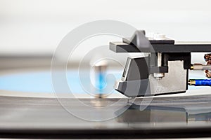 Stylus on vinyl record. Close up of turntable cartridge with needle and lp plate, blurred background, copy space