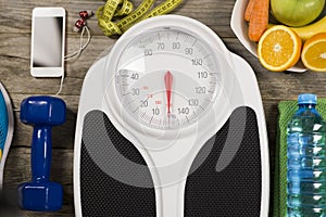 Analogue weight scale, gym object and healthy fruits on wooden background, healthy lifestyle concept