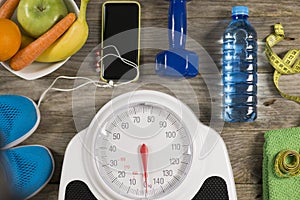 Analogue weight scale, gym object and healthy fruits on wooden background, healthy lifestyle concept