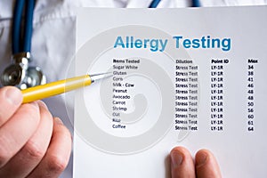 Analysis and testing for allergies photo concept. Doctor points with pen in his hand on result of patient allergy test in foregrou photo