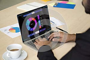 Analyst working with business analytics and data management system on computer, make a report with KPI and metrics connected to