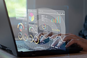 Analyst working on laptop showing business analytics data and data management system with KPIs and metrics connected to financial