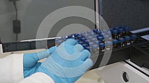 Analytical chemist puts a vials to auto sampler of HPLC system.
