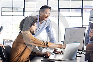 Analyzing data on computer screen, colleagues collaborating on project in office