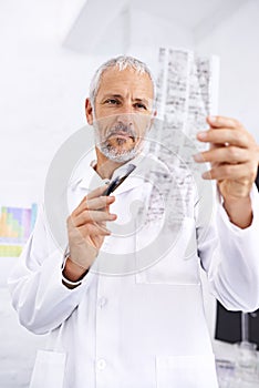 Analyzing DNA information. Shot of a male scientist examining the results of a DNA test.