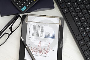 Analyzing financial report data  balance sheet, income statement with glass, notebook, calculator and keyboard