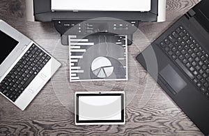 Analyzing investment charts with printer and laptop