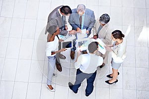 Analyzing the quarterly results. a group of diverse businesspeople discussing paperwork in a meeting.