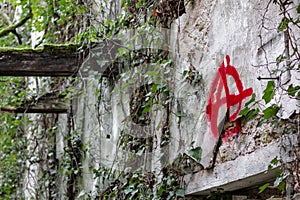 The `Anarchy` symbol graffitied in a ruined