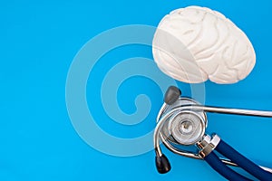 Anatomic study model of brain and stethoscope on blue background occupy half of photo, in second half - empty space for titles. Me photo