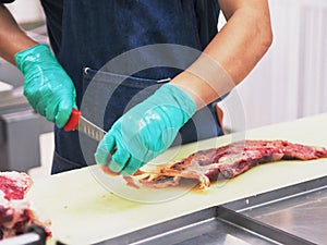 Master chef butcher is dissecting part of meat tenderloin , slicing membrane. photo