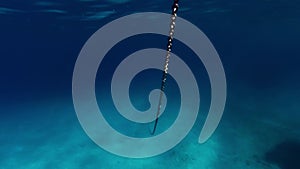 An anchor chain goes deep into a bay with blue water