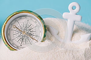 Anchor and compass in white sand isolated on blue