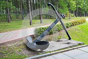 Anchor ocean ship in the Park on a background of green trees.