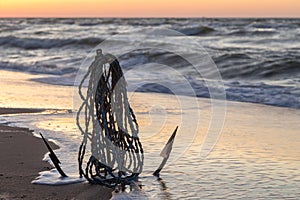 Anchor in the sand by the ocean, seascape at sunrise