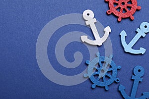 Anchor and ship wheel figures on blue background, flat lay. Space for text