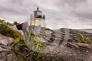 An anchor stands out in the dramatic rocky coastline at Castle Hill Lighthouse in Newport, Rhode Island, under a stormy sky