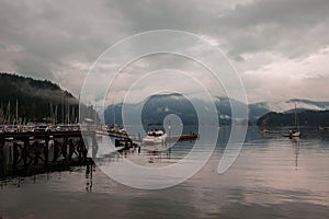 The anchor yacht in harbor  After rain cloudy sky, misty forest mountains and calm water.